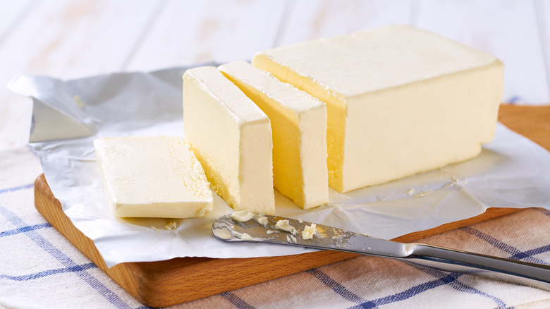 A sliced stick of butter on a cutting board with a knife.