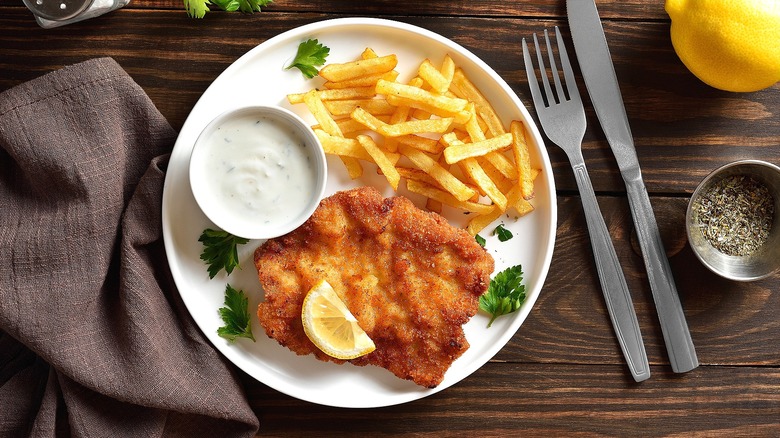 Plate of Wiener schnitzel and fries served with a creamy dipping sauce