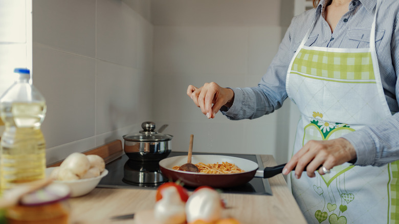 Woman adding pinch of salt to dish