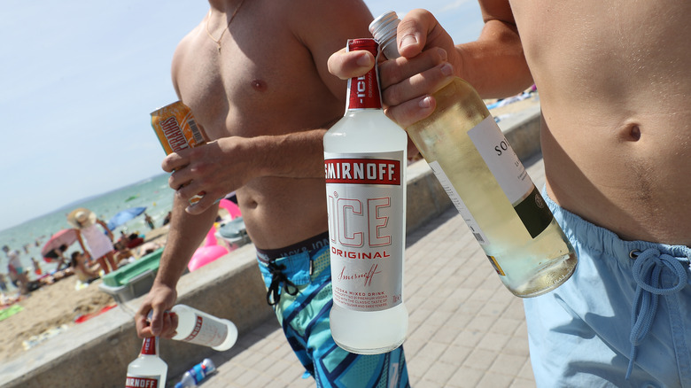 Two people in swimsuits carrying drinks