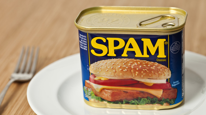 Can of spam on dinner plate with fork on wood table