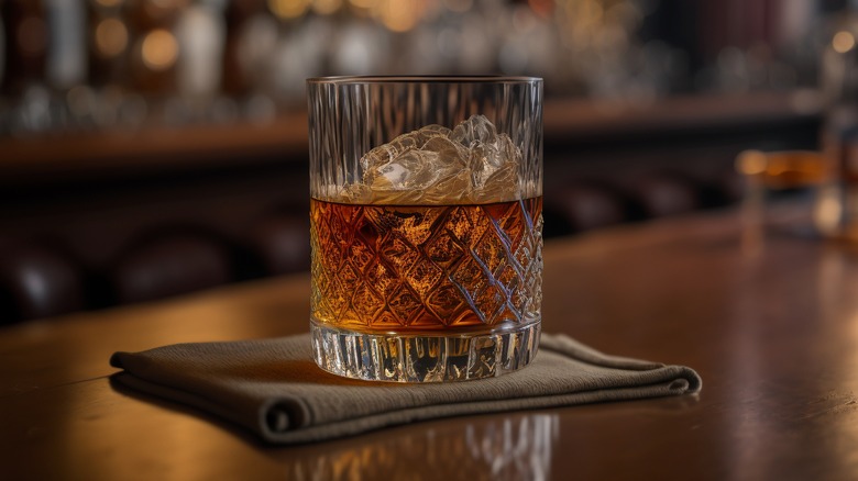 glass of whiskey resting on napkin on bartop