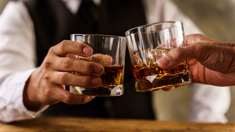 two hands toasting with whiskey