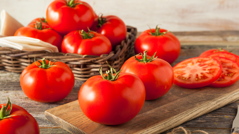 Large beefsteak tomatoes in kitchen basket and on cutting board