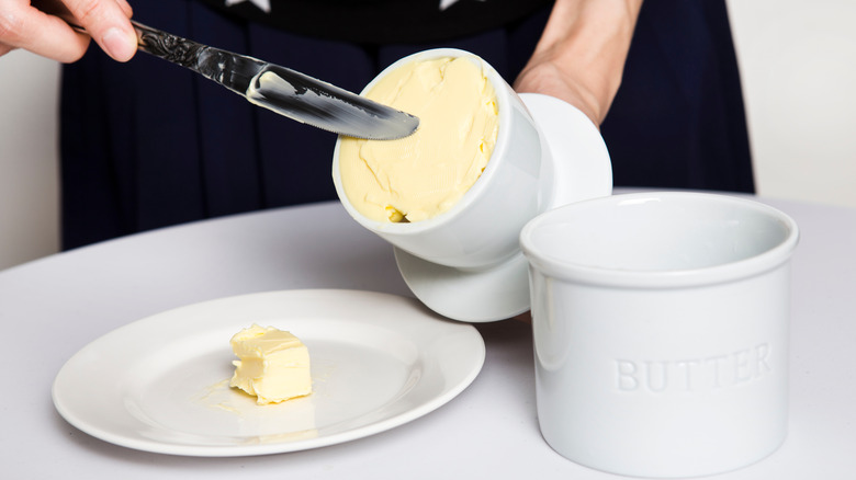 A person spreads butter from a butter bell.