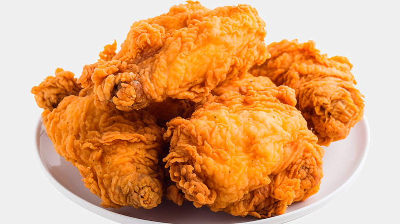 A pile of crispy fried chicken on a white plate and white background