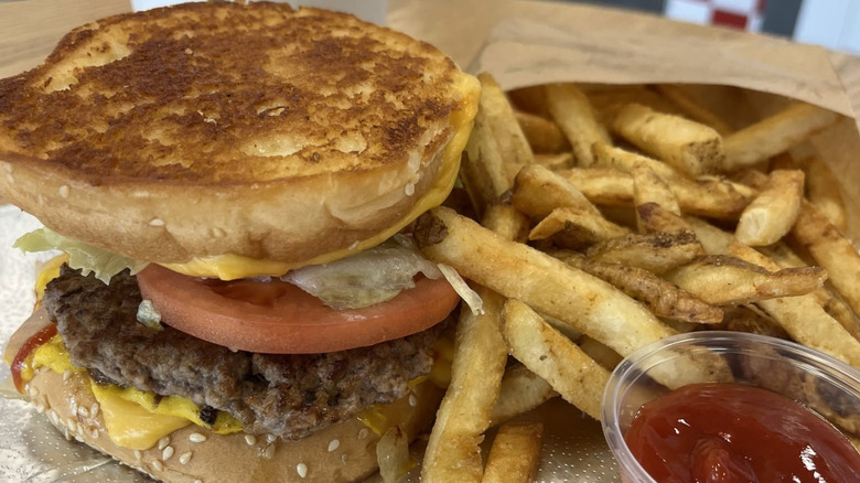 A sandwich and bag of fries sit on a table at a Five Guys.