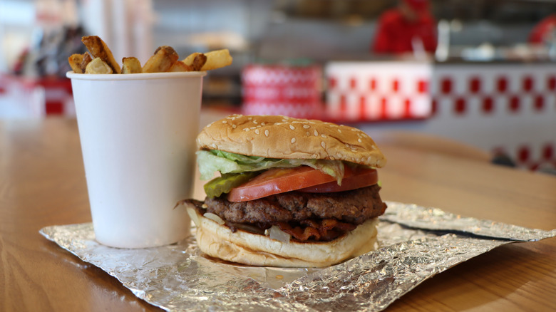 Five Guys fries sit in a cup next to a burger.