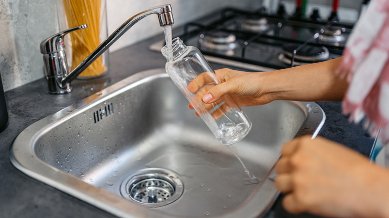 Woman washing reusable water bottle