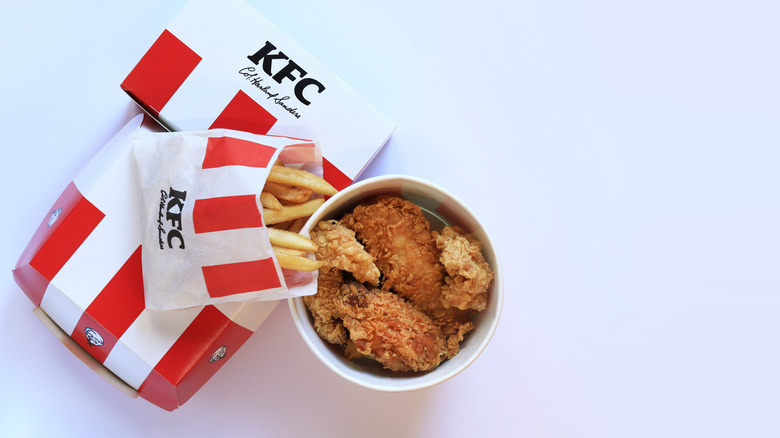 A typical KFC meal of a chicken bucket, fries, and a drink.