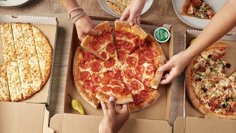 Hands grab Papa John's pizza
