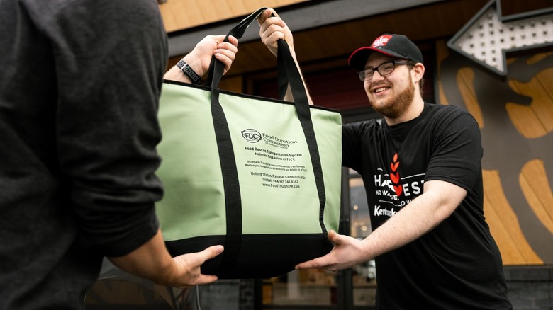 A Harvest/FDC employee-volunteer accepts a bagged donation.