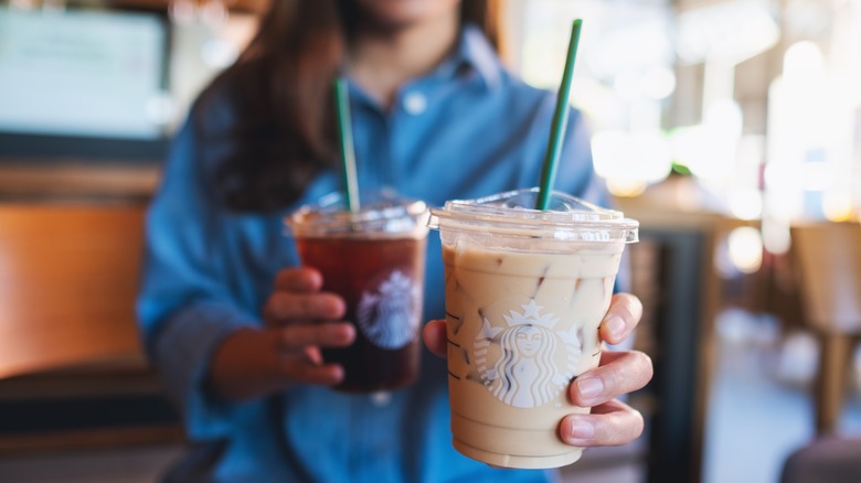 Woman holding two Starbucks drinks
