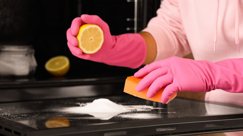 a person with pink gloves cleaning with a lemon and salt