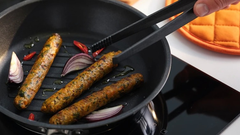 IKEA veggie dogs cooking in a pan with oil and onions