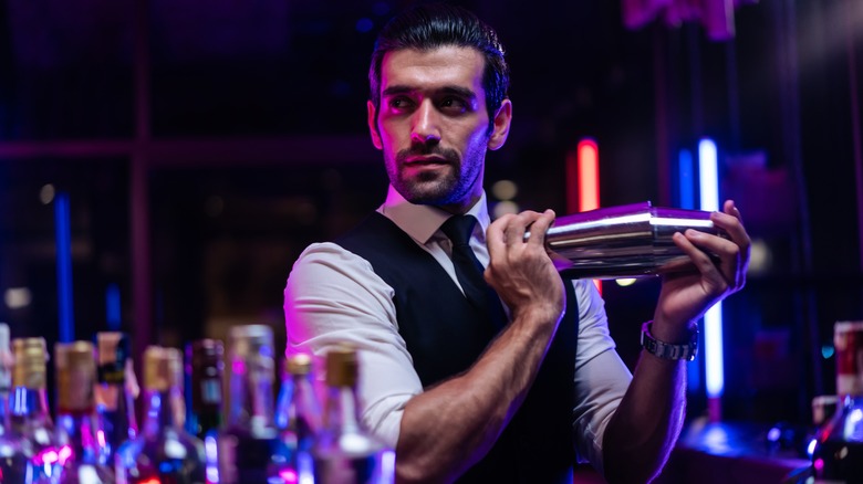 bartender shaking a cocktail in a metal shaker