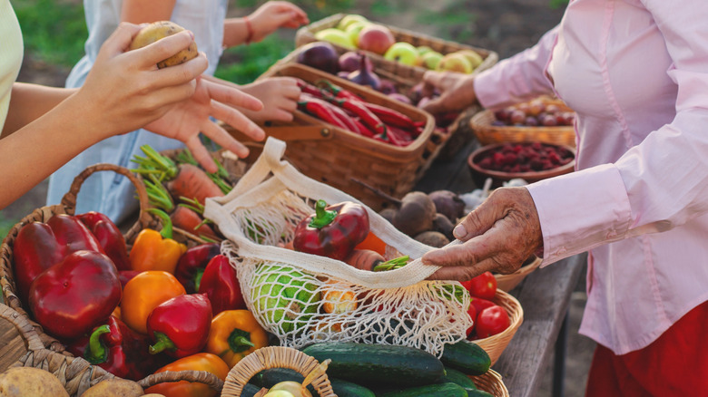 People interacting over a selection of farm-fresh produce at a market.
