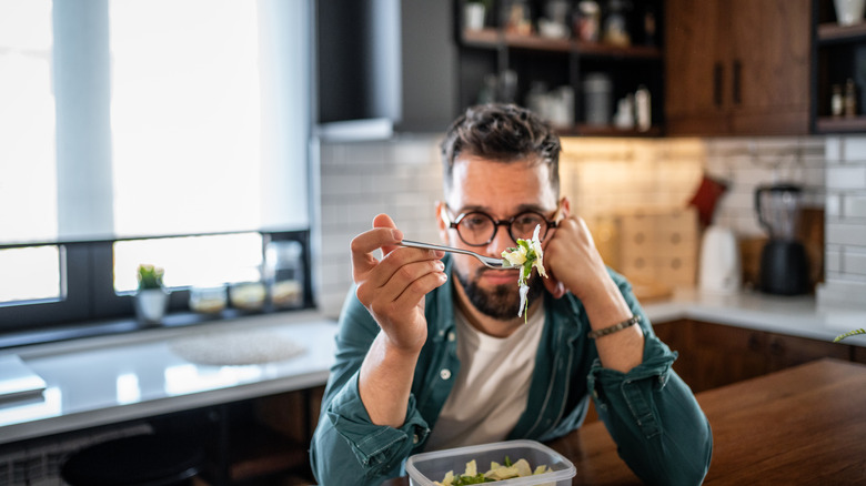 A diner hesitating to eat the salad on their fork.