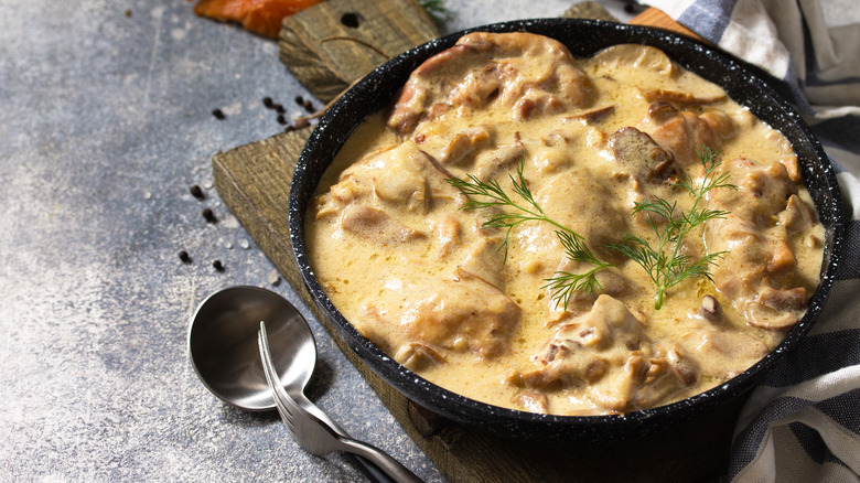 chicken fricassee in black bowl with dill fronds