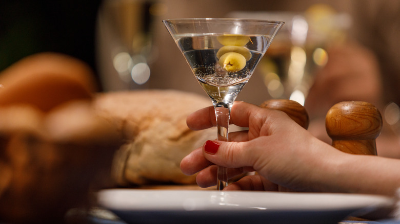 person holding martini with olives