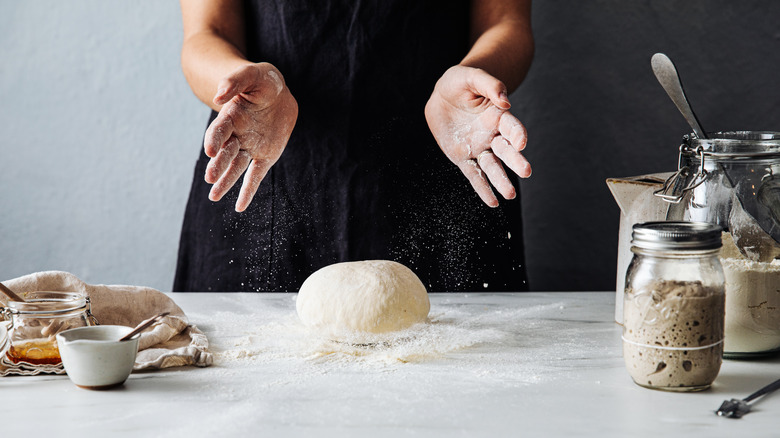 Baker making sourdough with jar of starter