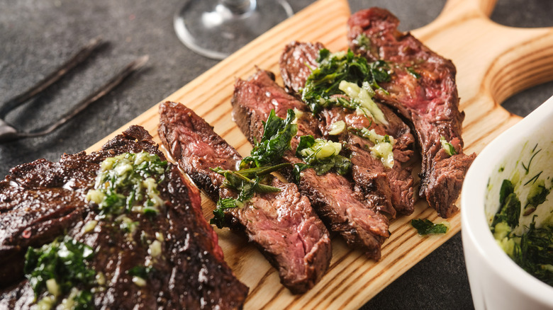 Sliced steak on board with chimichurri sauce
