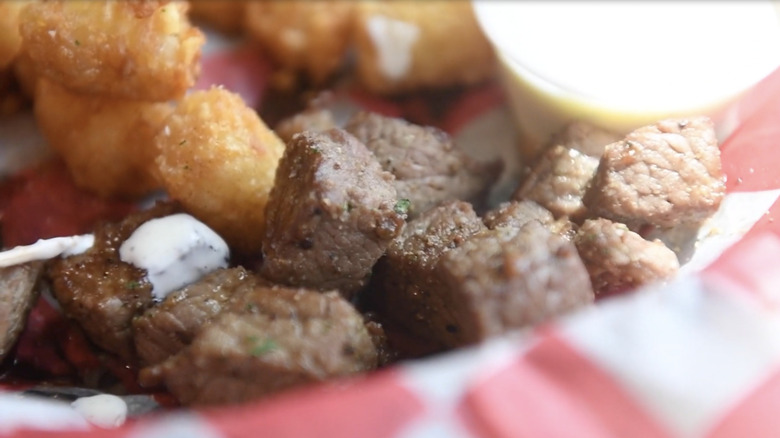 Cubes of chislic meat in basket with tater tots