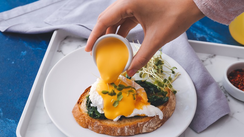 Pouring sauce on Eggs Florentine 