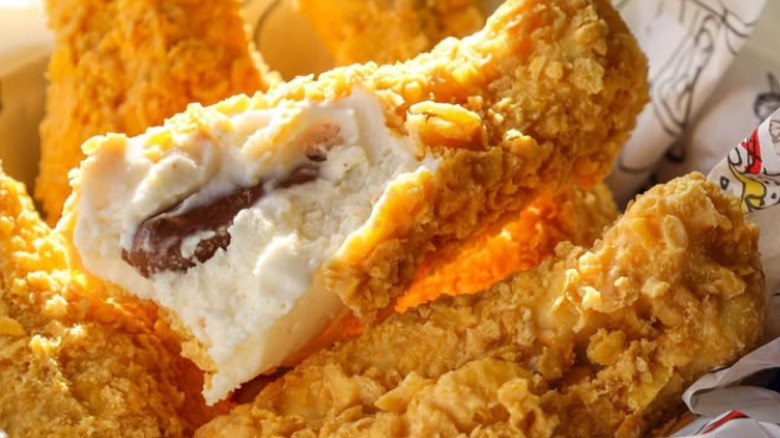 Ice cream that looks like a chicken drumstick bitten into in a basket with several other drumsticks