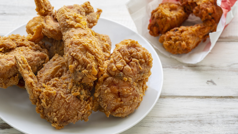 A plate of fried chicken with a bag of chicken in the background