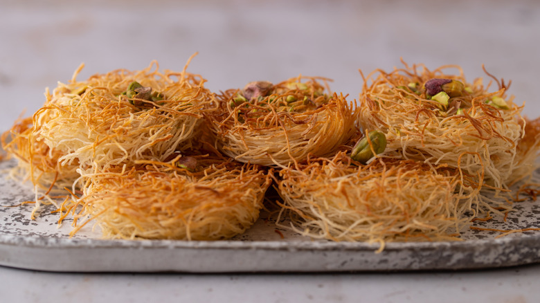 Kataifi balls topped with pistachio on a serving platter