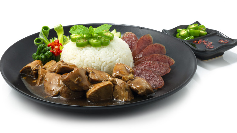 Sliced lap cheong, rice, and stew on black plate