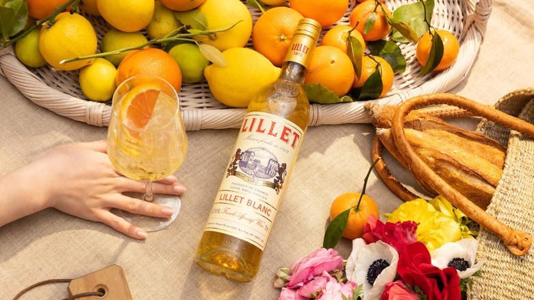 Bottle of Lillet Blanc on a table with citrus fruits and a Lillet cocktail