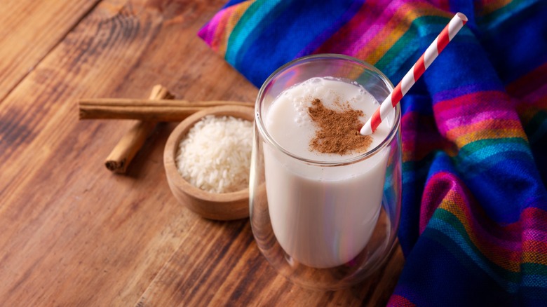 Glass of horchata, cinnamon sticks, and bowl of rice