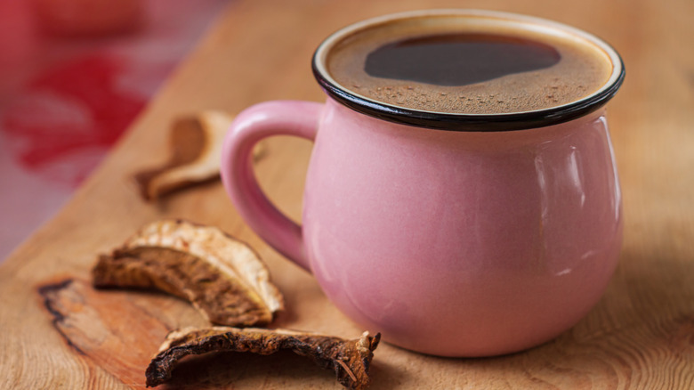 pink mug of mushroom coffee with dried mushrooms