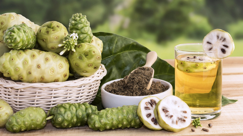 A basket of noni fruits with a glass of juice