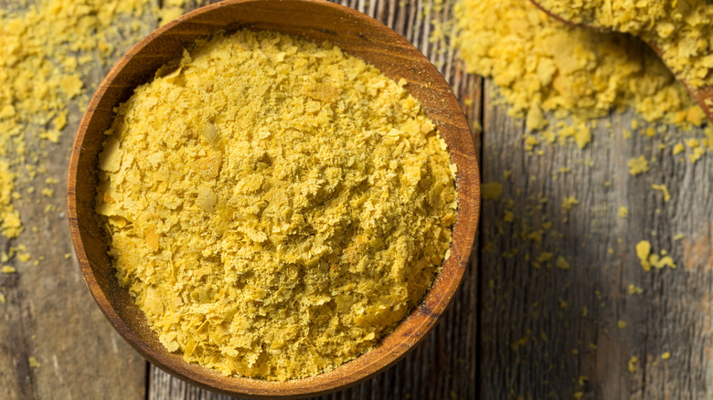 Yellow nutritional yest flakes in a wooden bowl on table