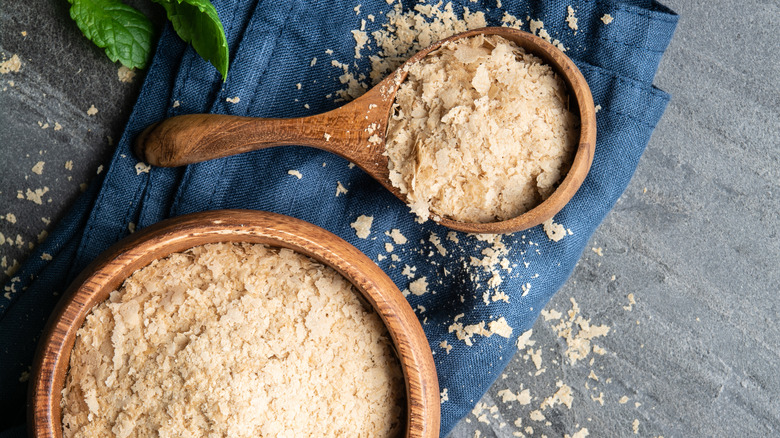 Nutritional yeast flakes in wood bowl and spoon 