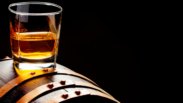 Glass of whiskey on top of barrel