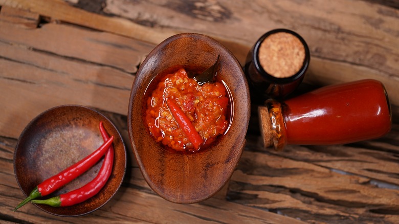 A bowl of sambal oelek next to chilies