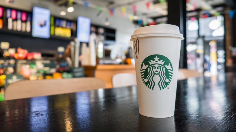 Close-up of a Starbucks cup with a drawn-on heart on top of a café table
