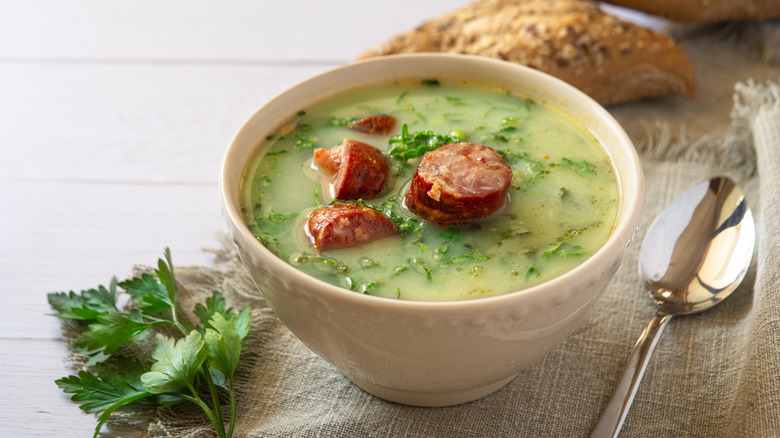 A bowl of caldo verde with greens and slices of sausage floating in the broth