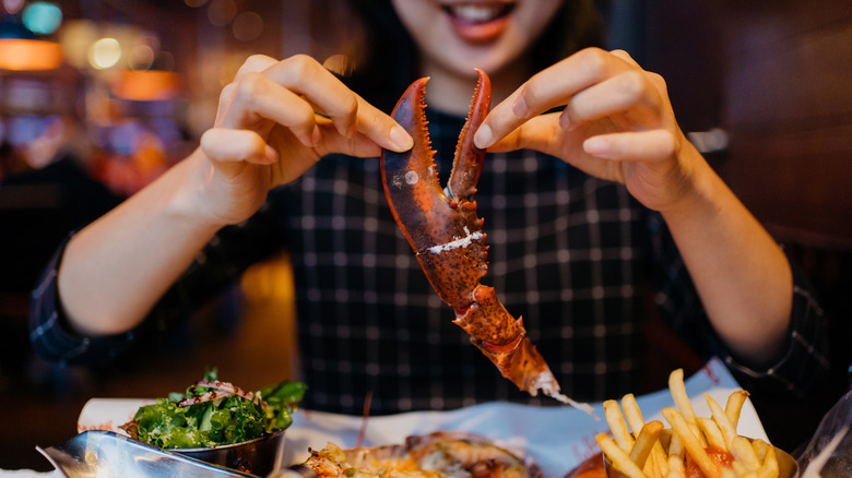 person holding lobster claw at dinner table