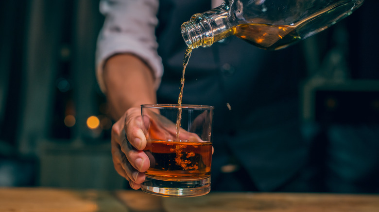 bartender pouring from bourbon bottle