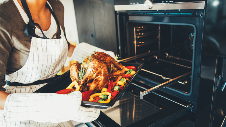 Person taking chicken out of oven