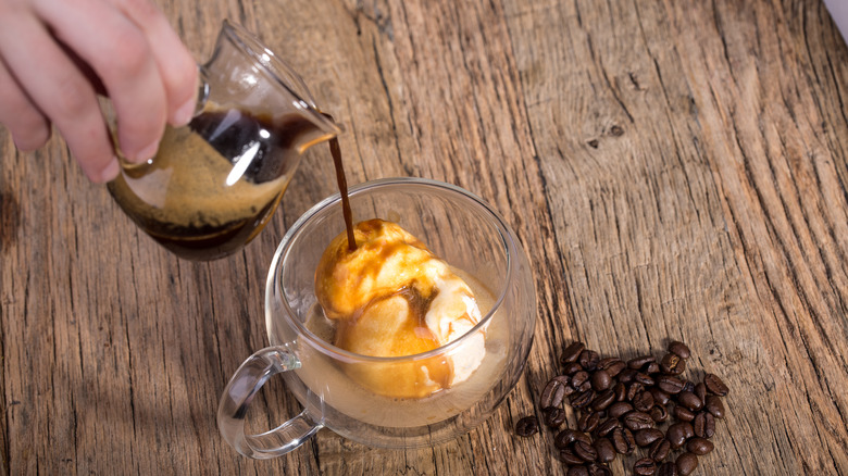 Hand pouring espresso over vanilla ice cream