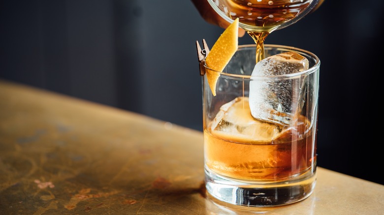 pouring whiskey cocktail into glass