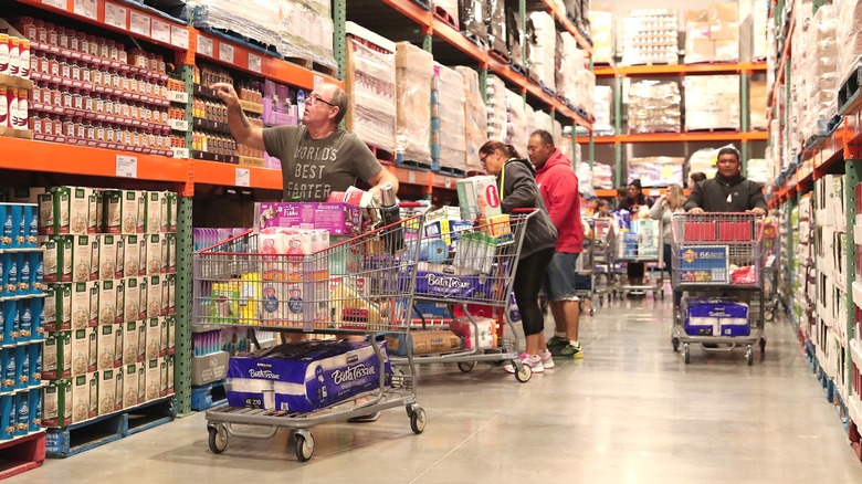 People with filled shopping carts in aisle at Costco
