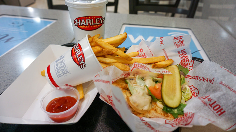 A loaded veggie sandwich with fries and a drink