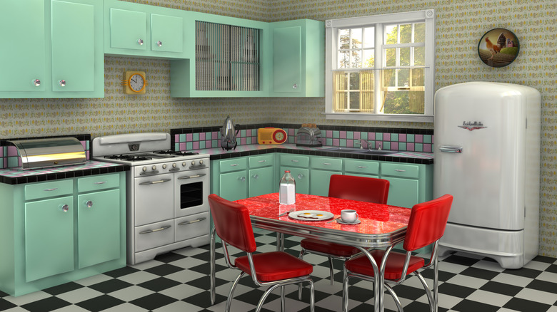 A kitchen with 1950s styling features mint-green cabinets and a red laminate table